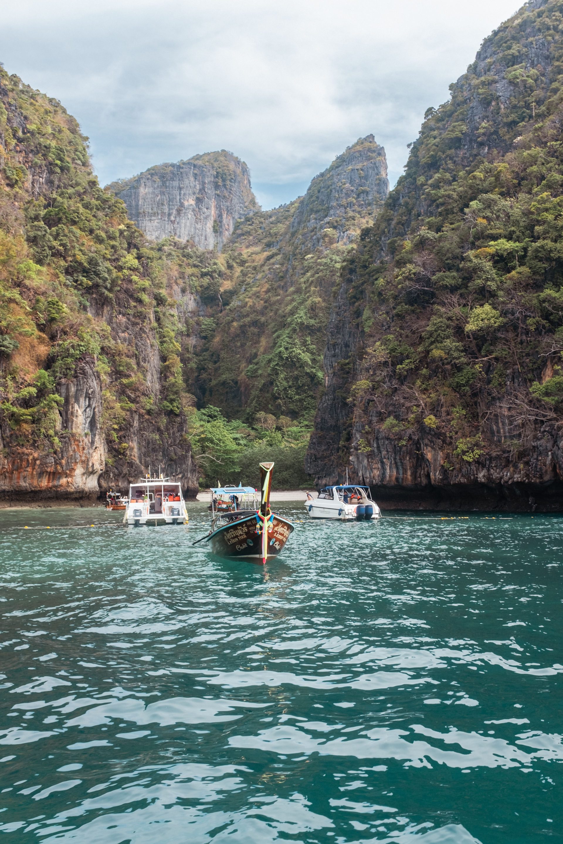 Boats entering a narrow lagoon between high rock walls