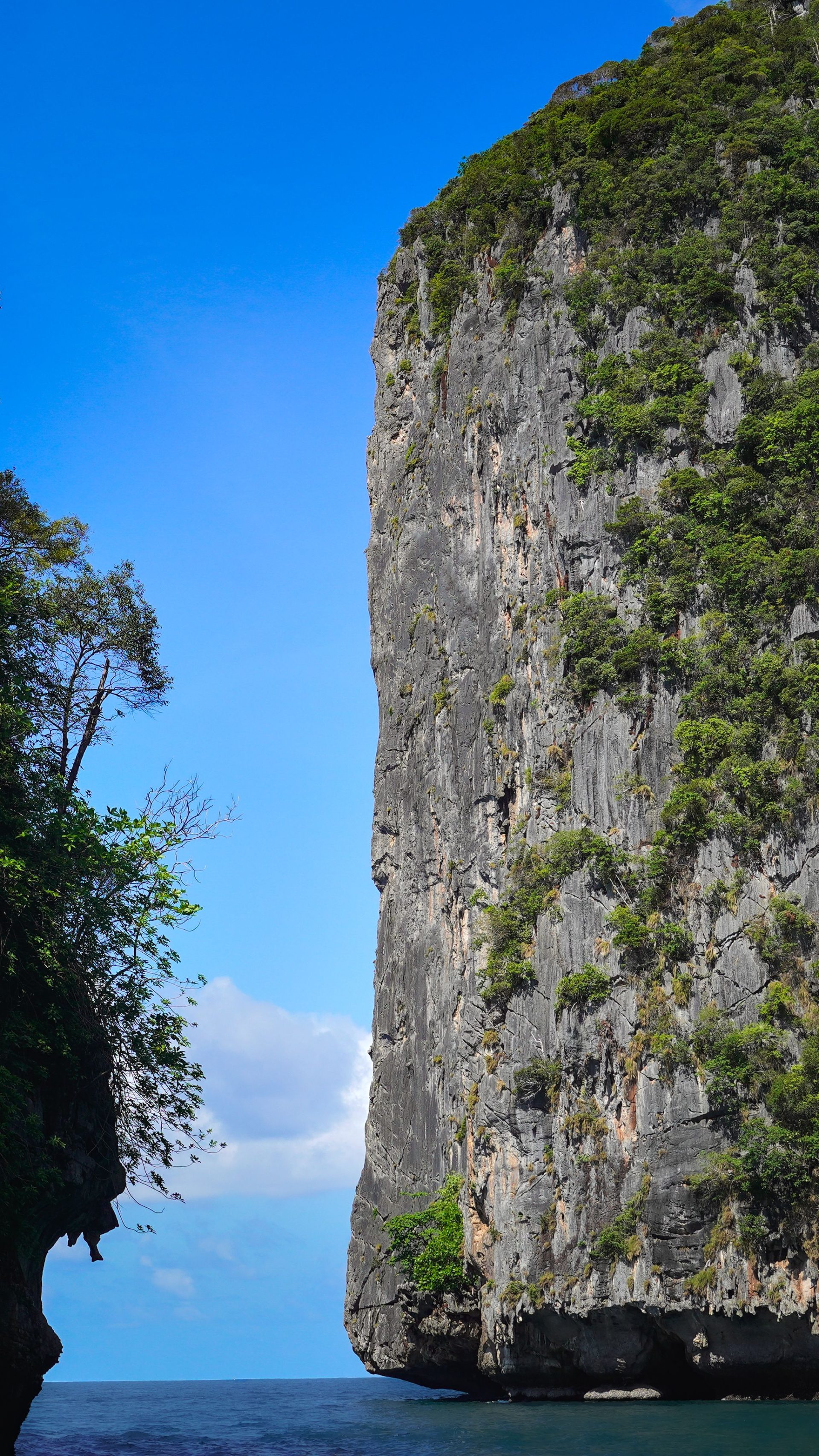 A limestone cliff rising straight out of calm water