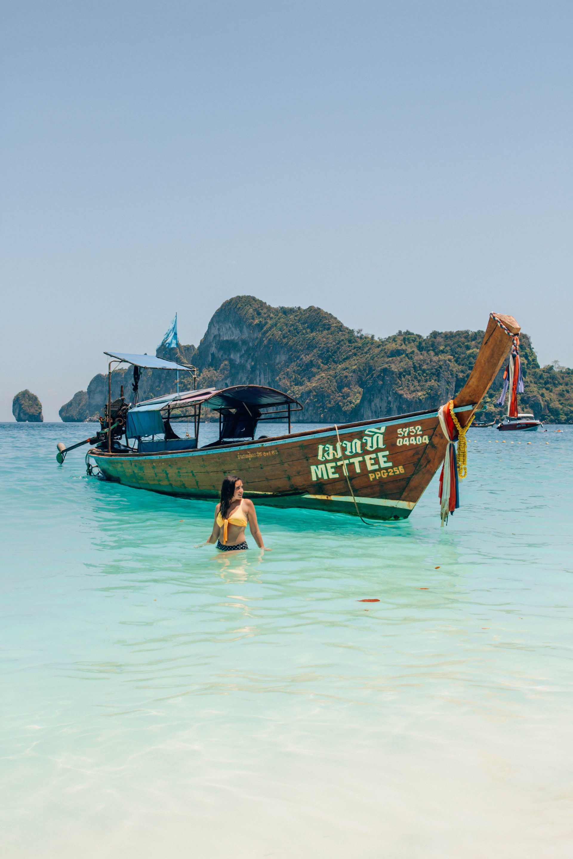 A longtail boat on turquoise water below limestone karsts