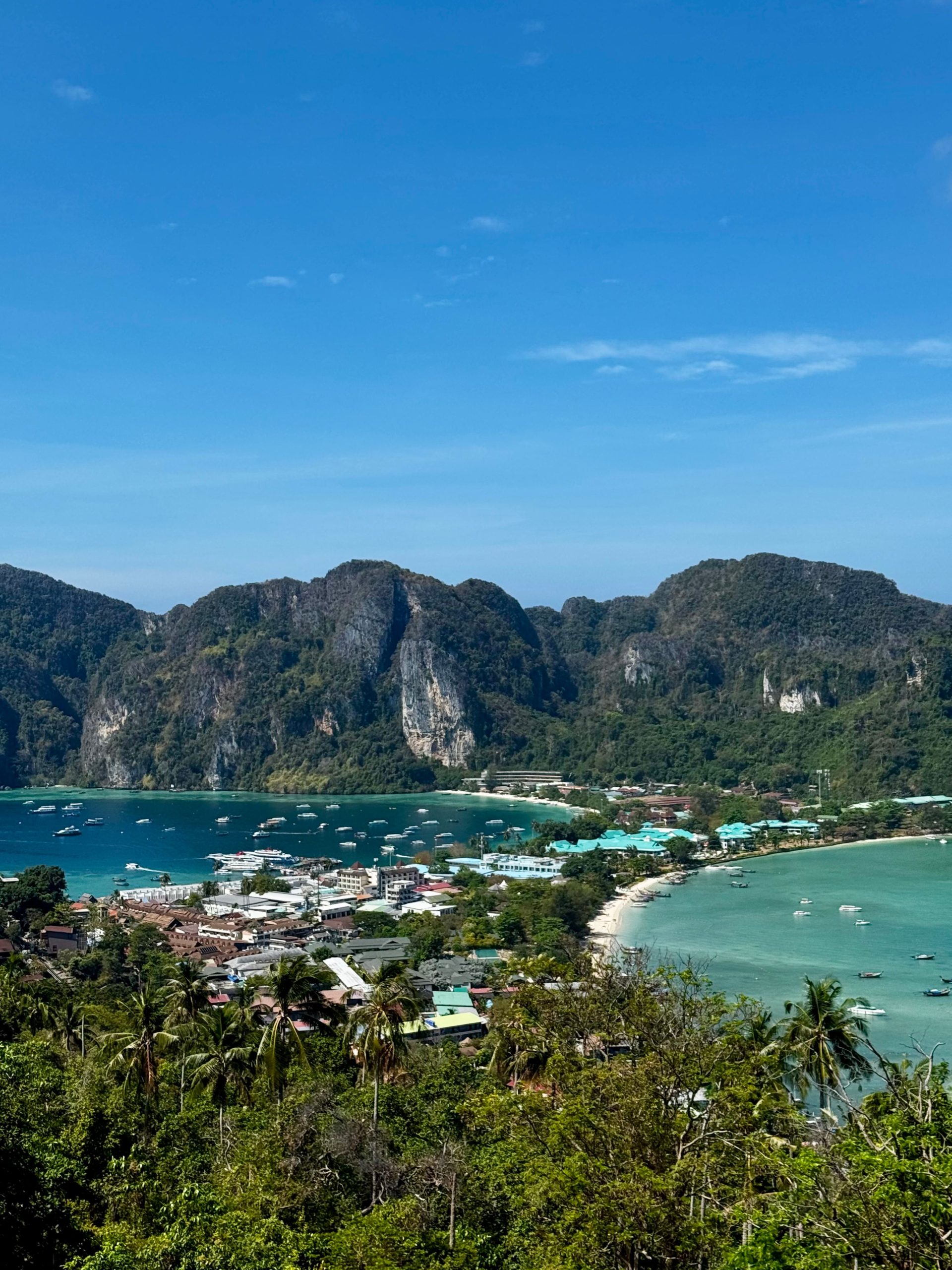 Aerial view of a curved bay between limestone cliffs with longtail boats