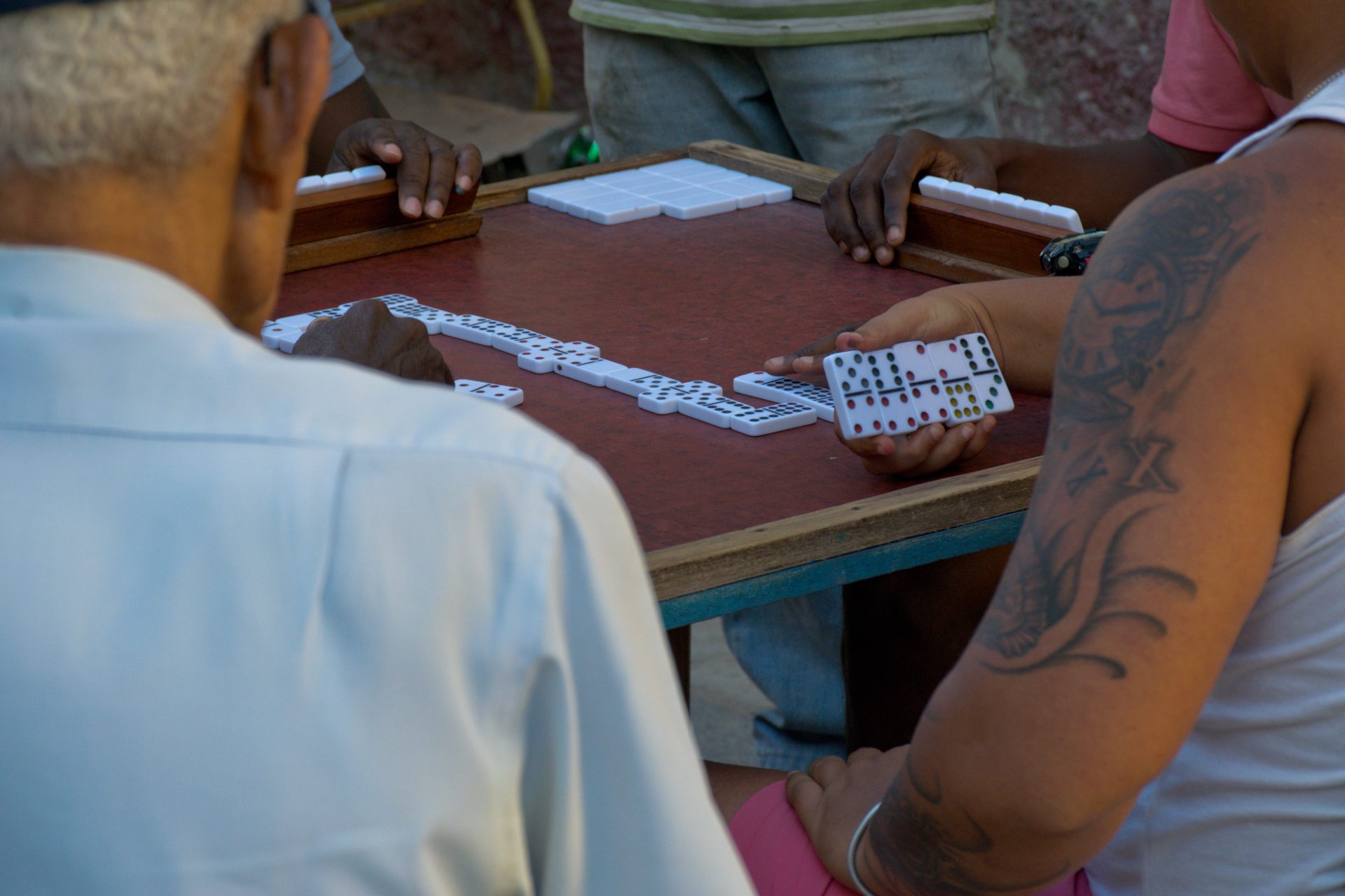 Hands playing a game of dominoes on a street table in Havana