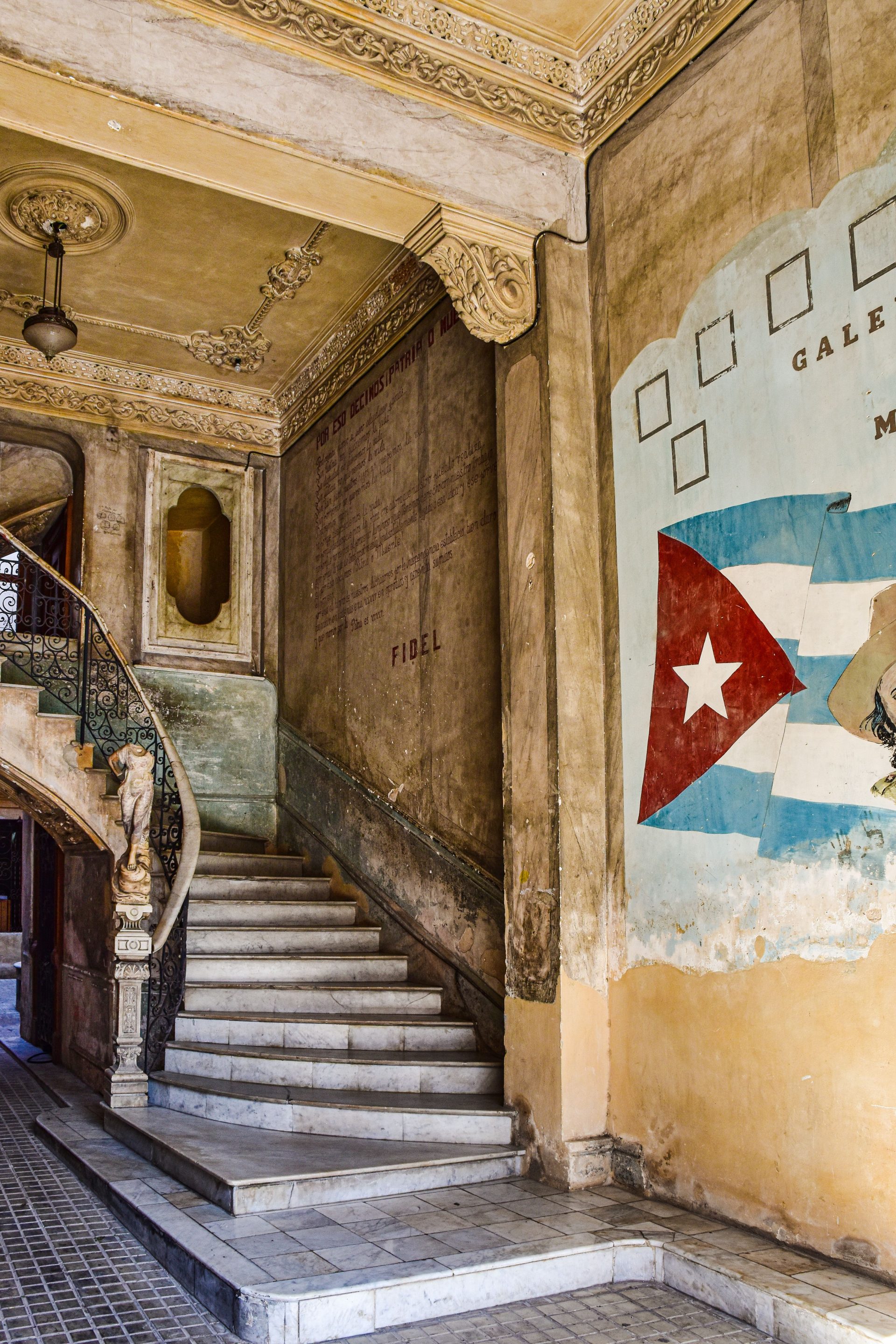 A grand interior staircase with a Cuban flag mural behind it