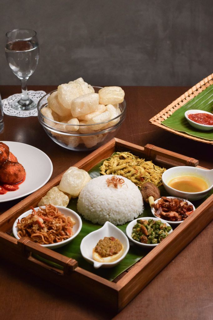 Balinese nasi campur tray with rice, sambal, crackers, and mixed side dishes