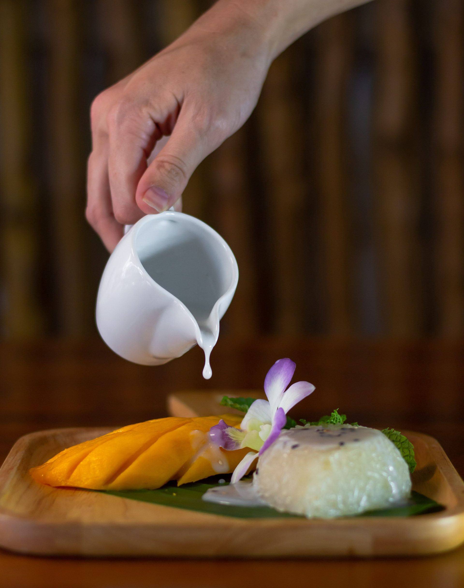 Mango sticky rice with coconut sauce being poured tableside