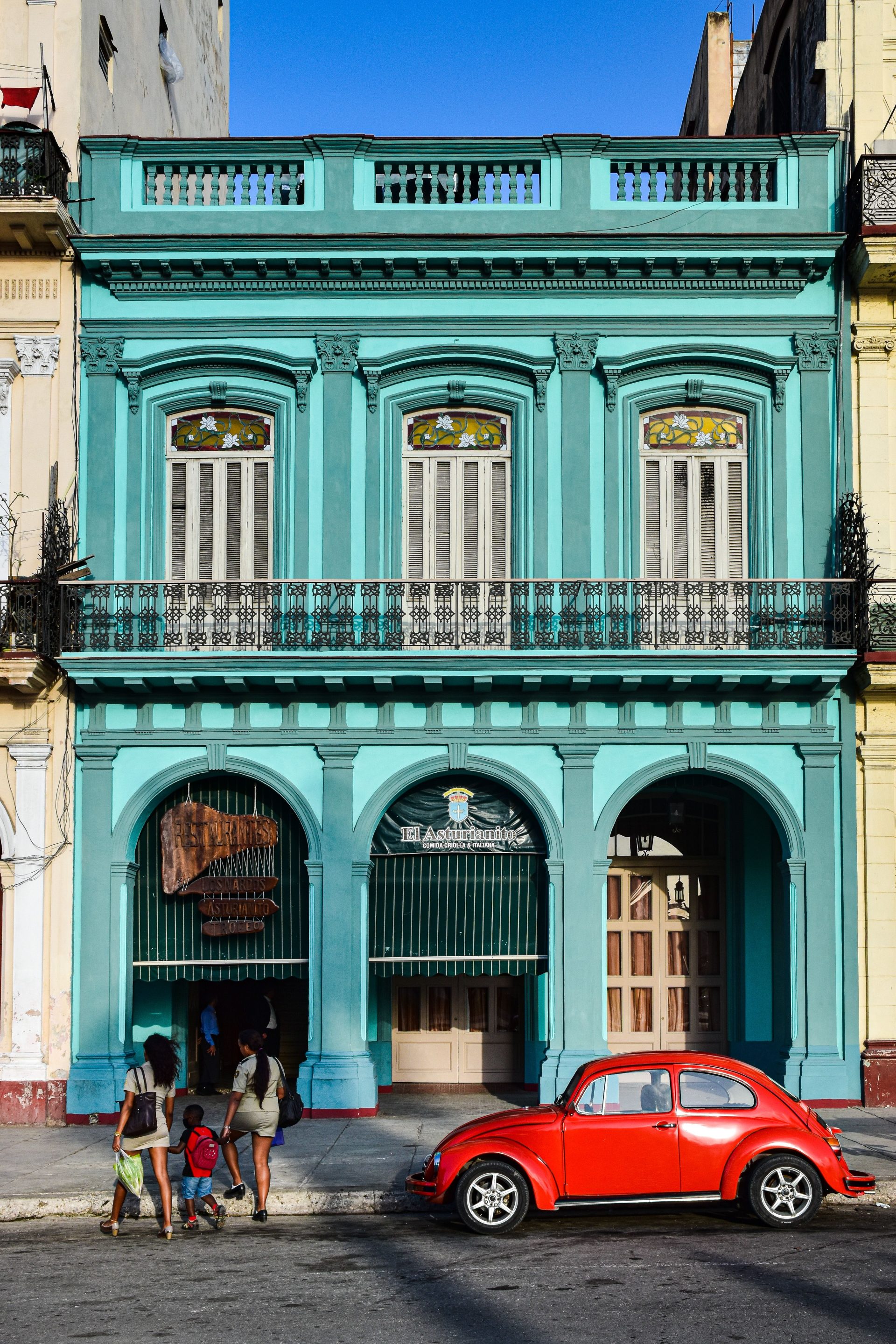 A turquoise colonial facade with tall shuttered windows
