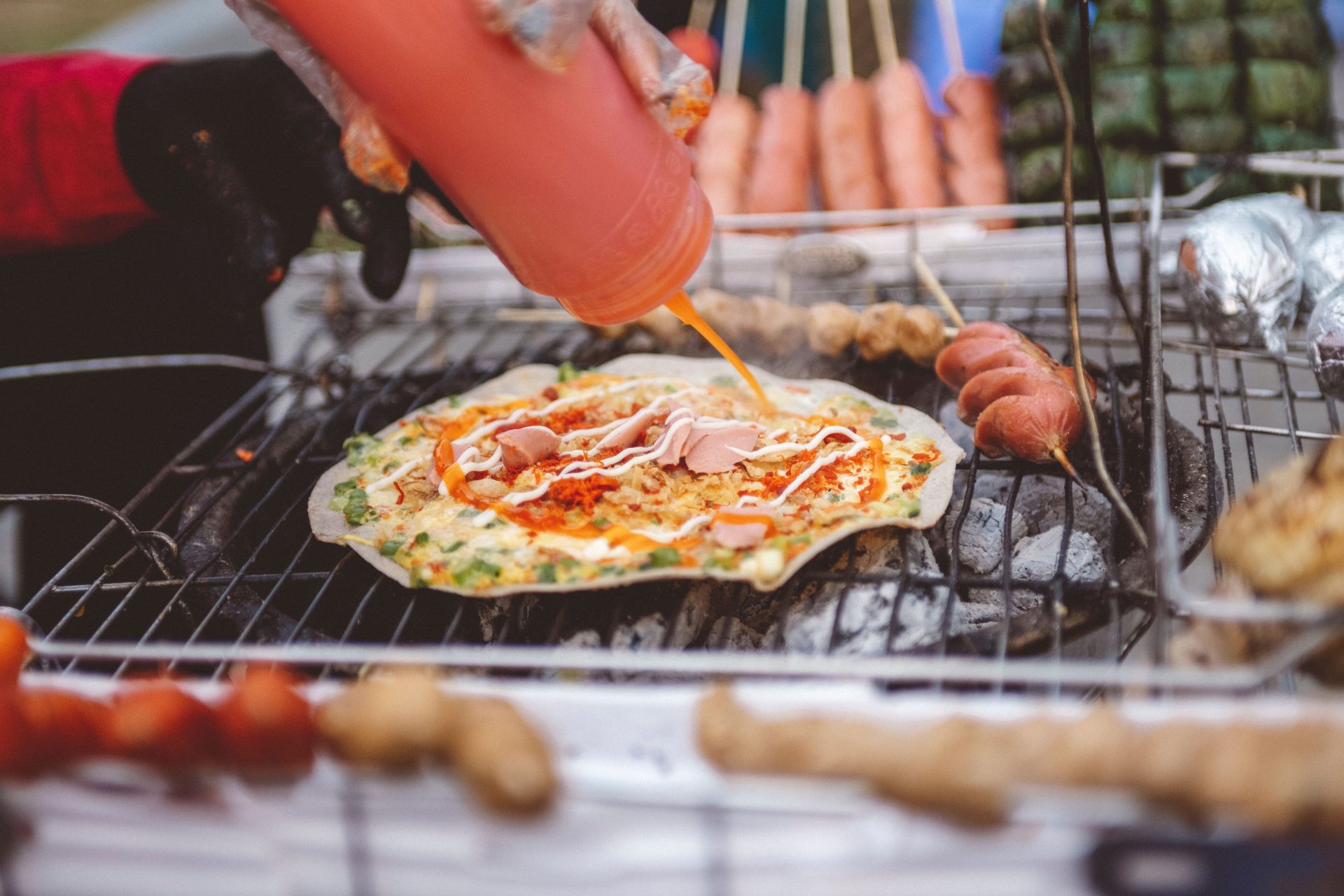 A street vendor grilling rice paper over charcoal