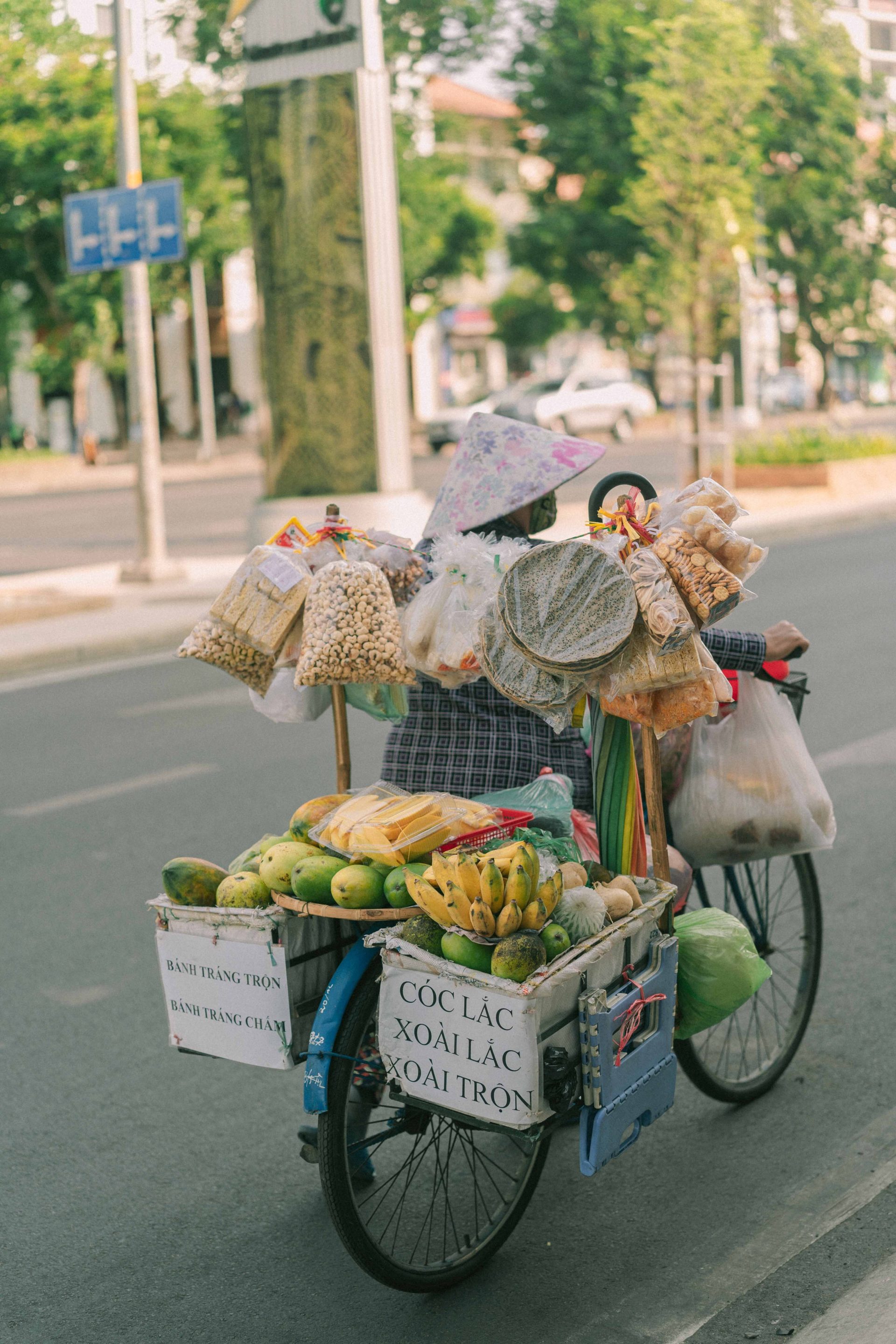 Vendors cycling with baskets of fresh produce on a Vietnamese street