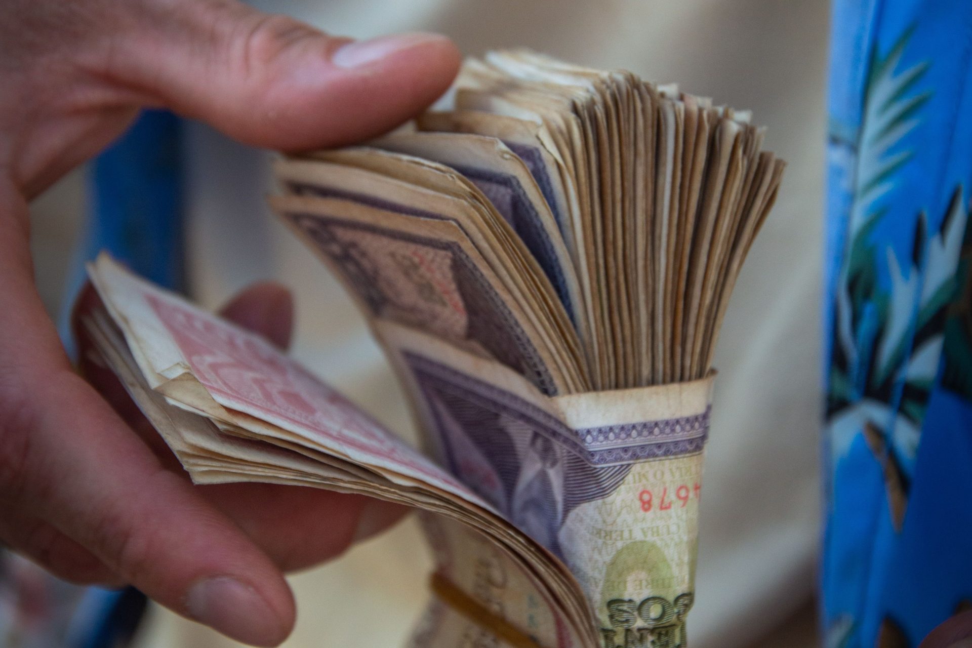 Close-up of individual organizing a large bundle of currency notes with both hands.