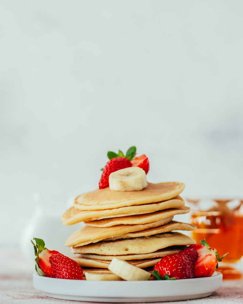 Stack of banana pancakes with strawberries and syrup