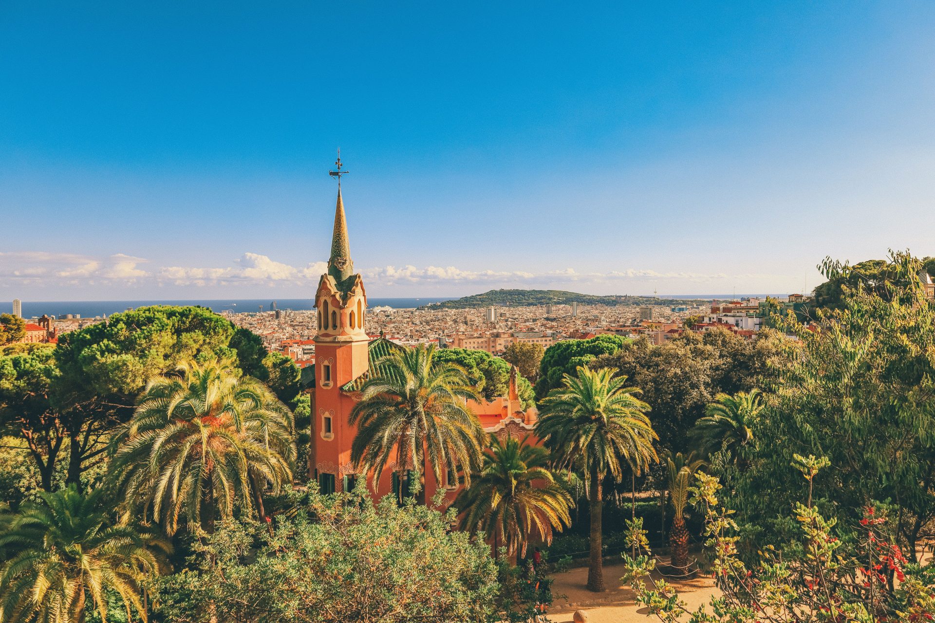 A view over Barcelona rooftops towards the hills with a church spire in the foreground