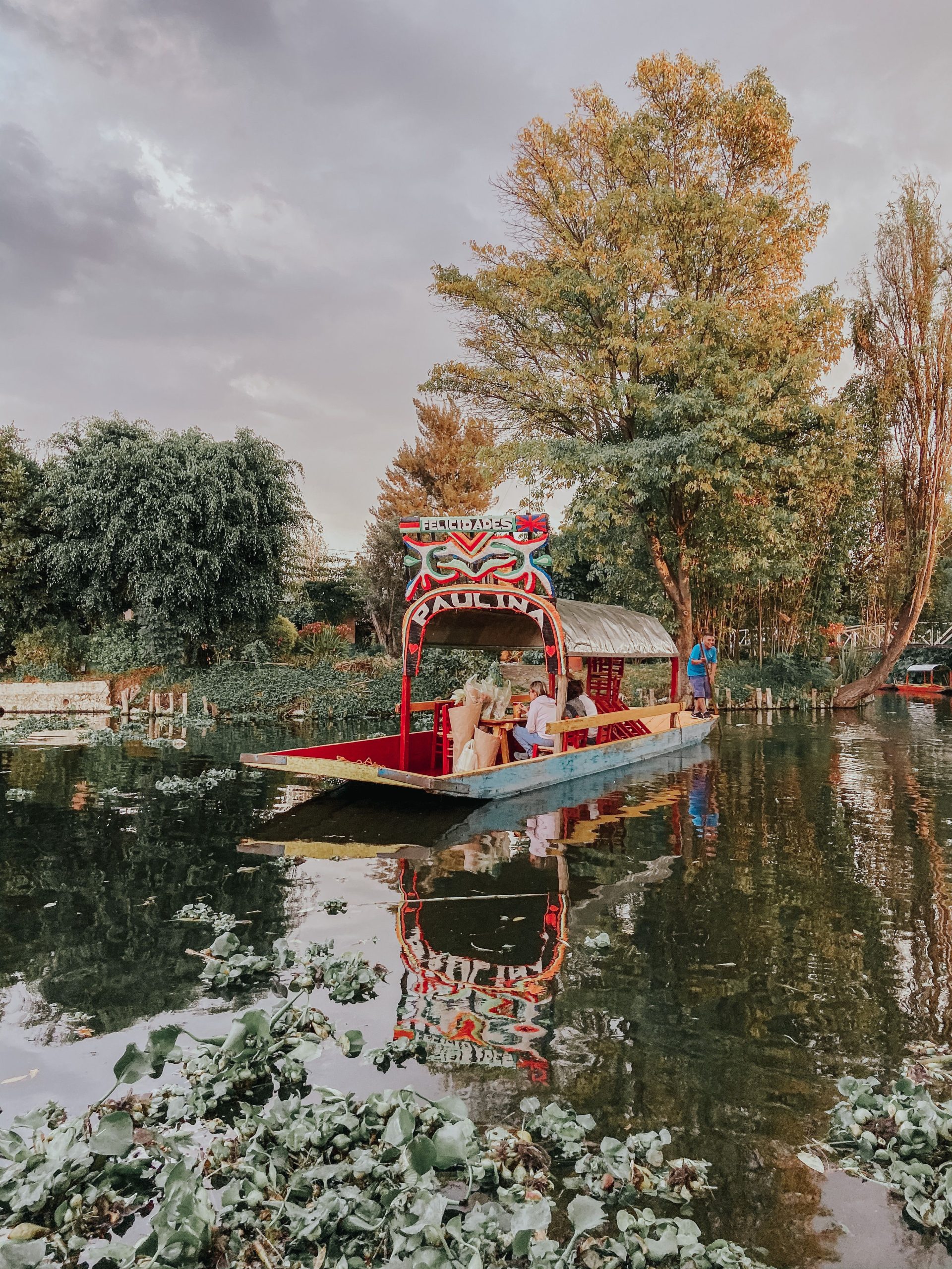 Trajinera boats on a tree-lined canal at Xochimilco
