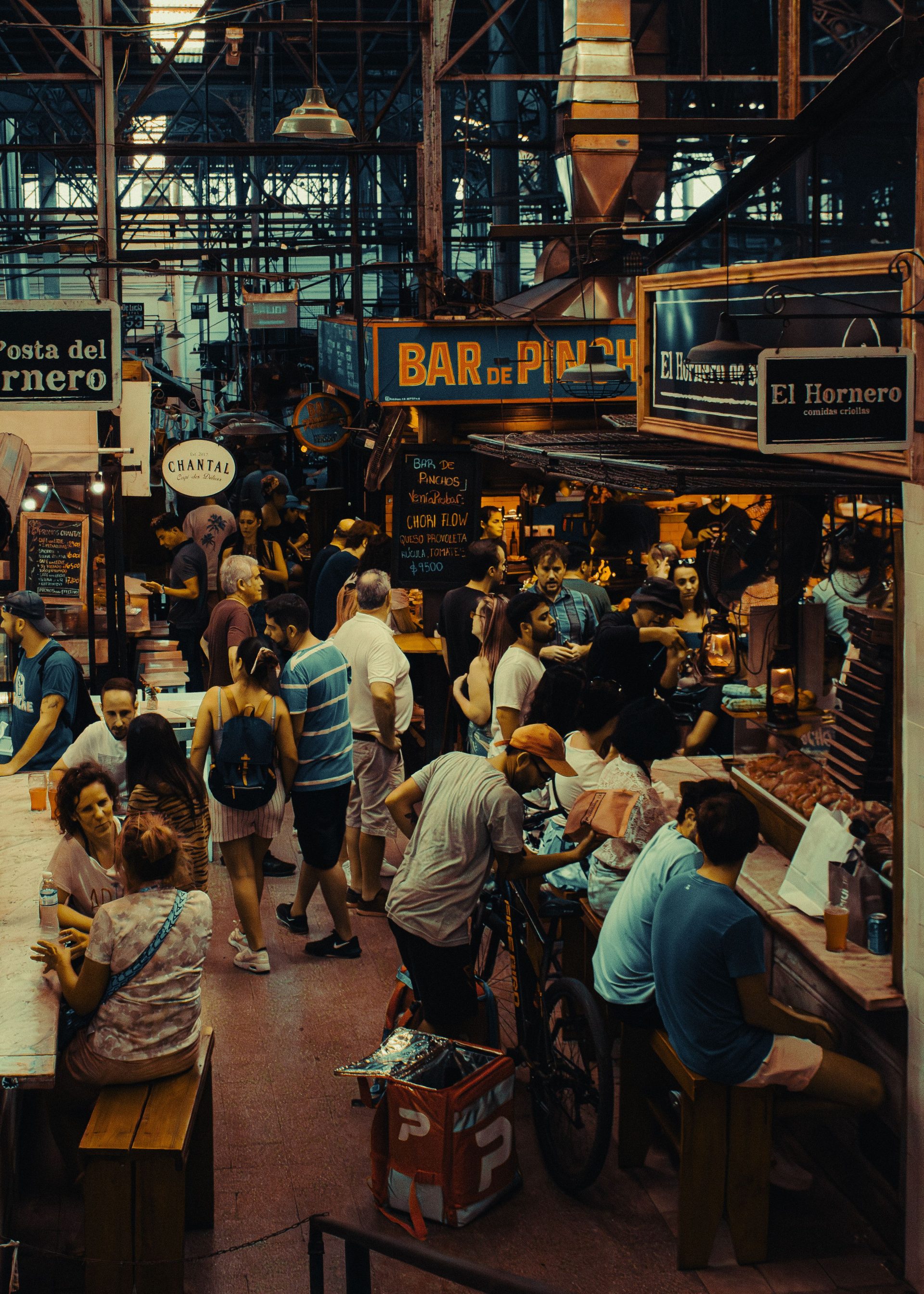 A crowded covered market hall with stalls under an ironwork roof