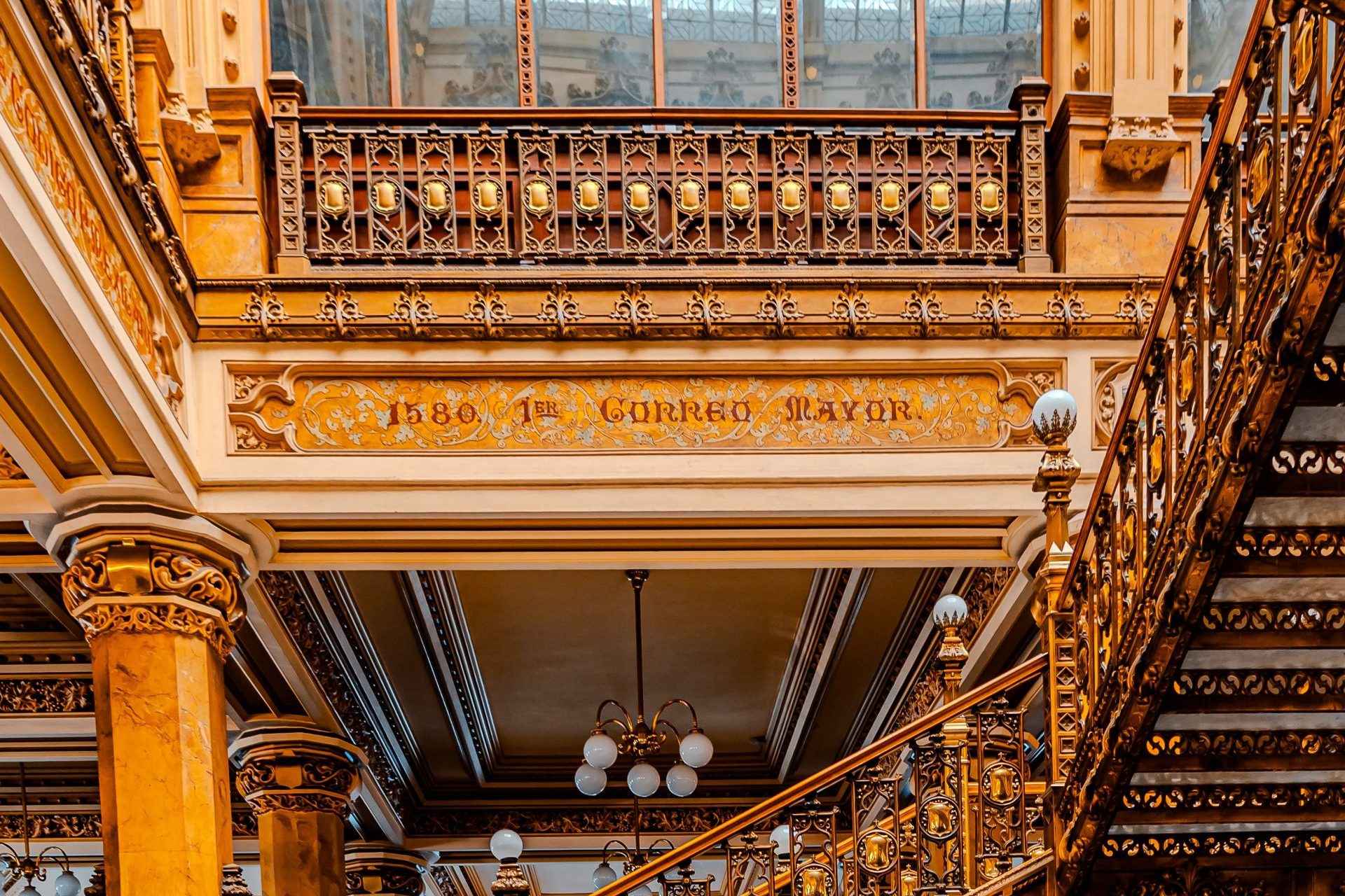 The ornate iron staircase and gilded balconies inside the Palacio de Correos