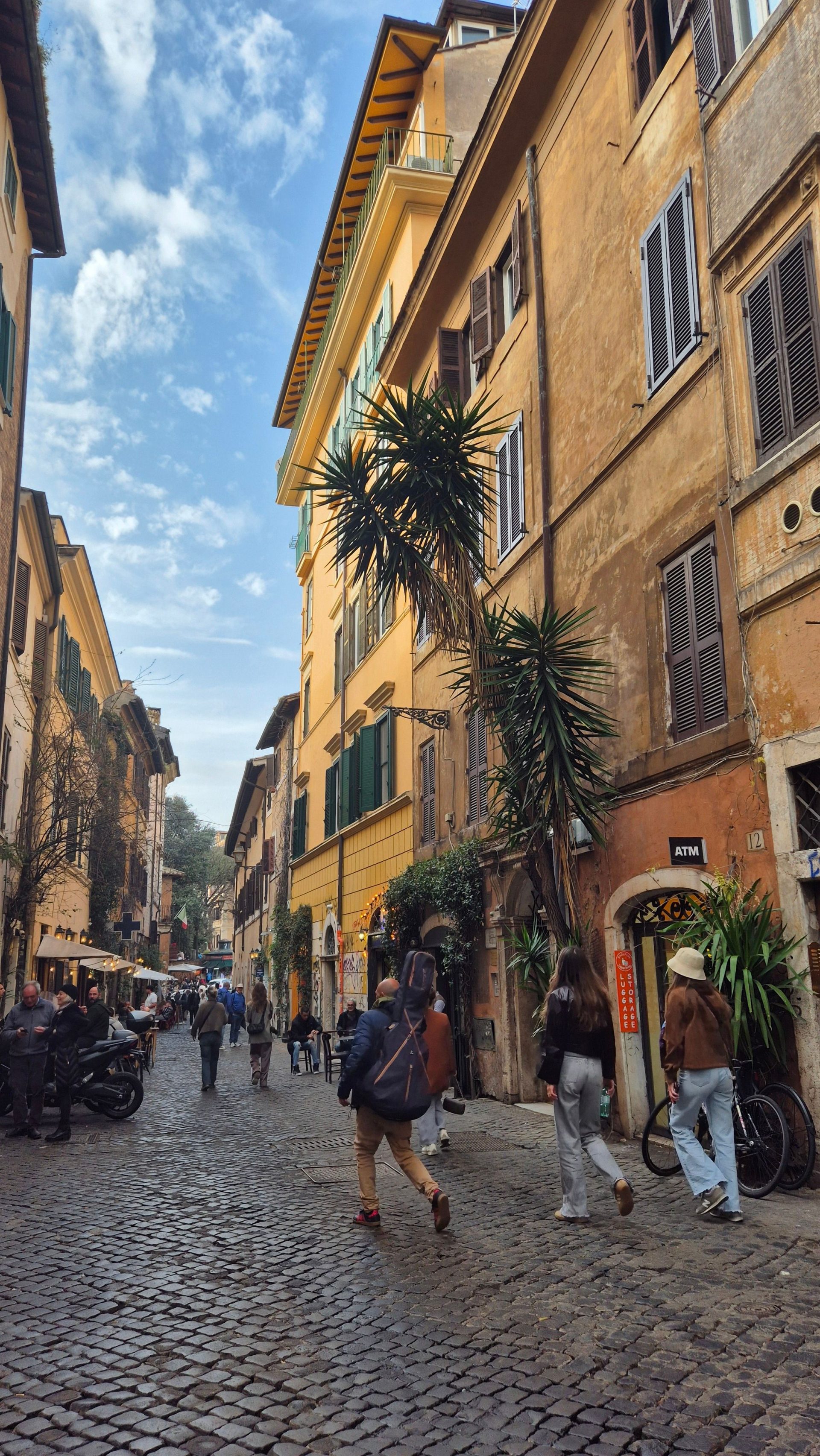A narrow cobbled lane between ochre buildings in Rome