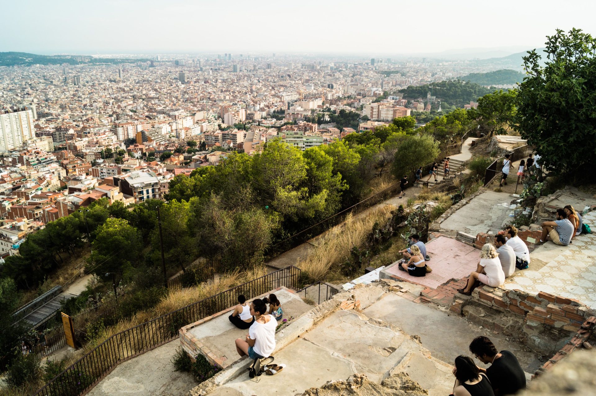 People sitting on a concrete viewpoint above Barcelona at sunset