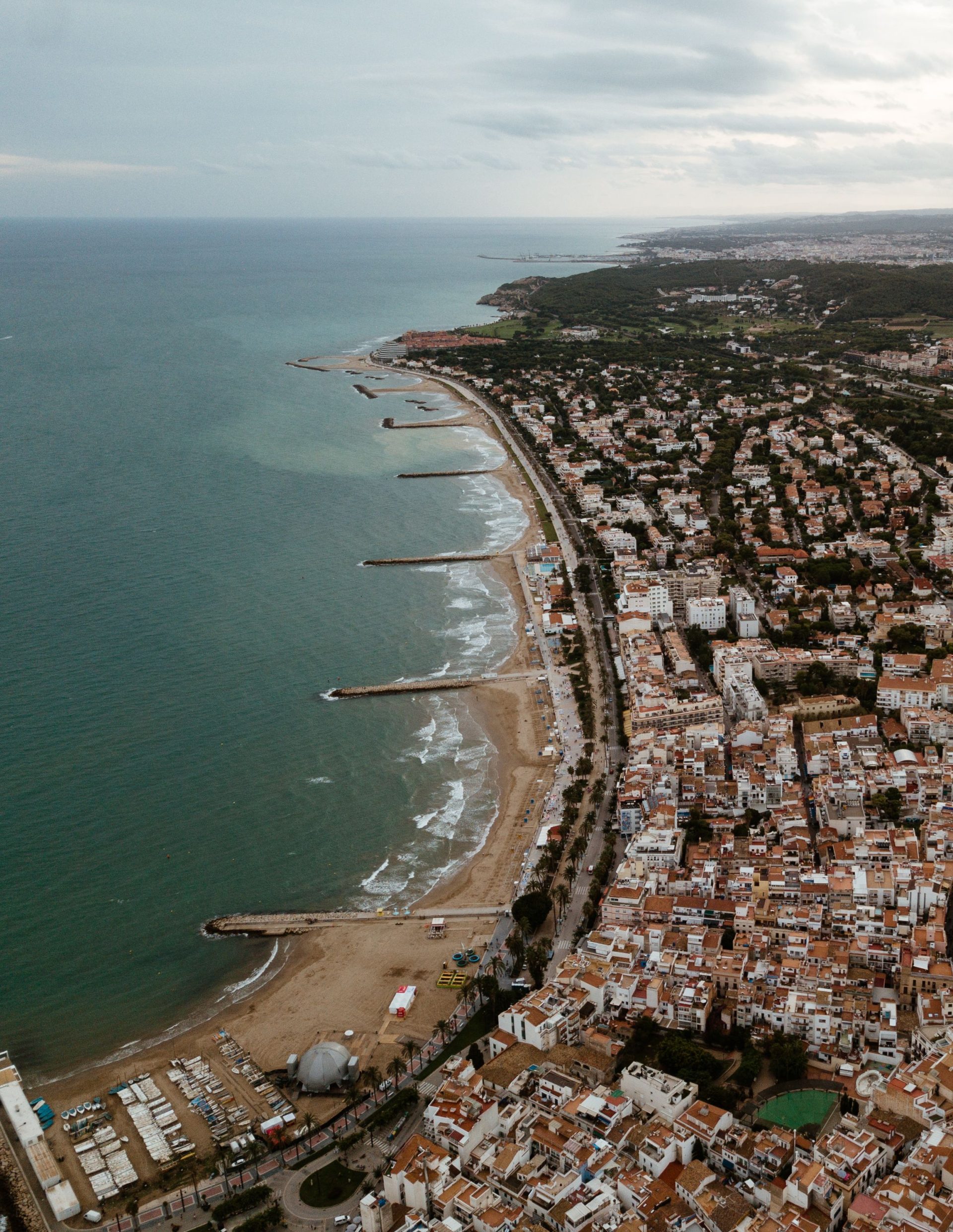 A beach below an old town promontory in Sitges