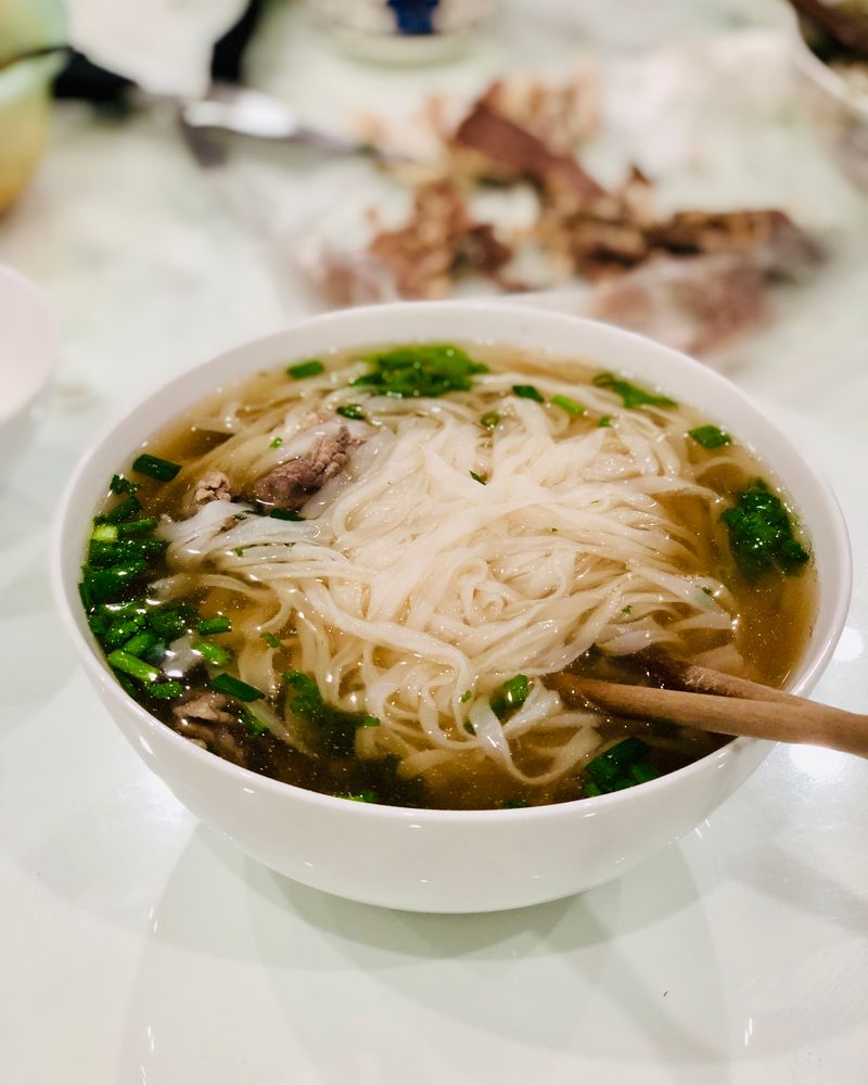Steaming bowl of Vietnamese phở with rice noodles and fresh herbs