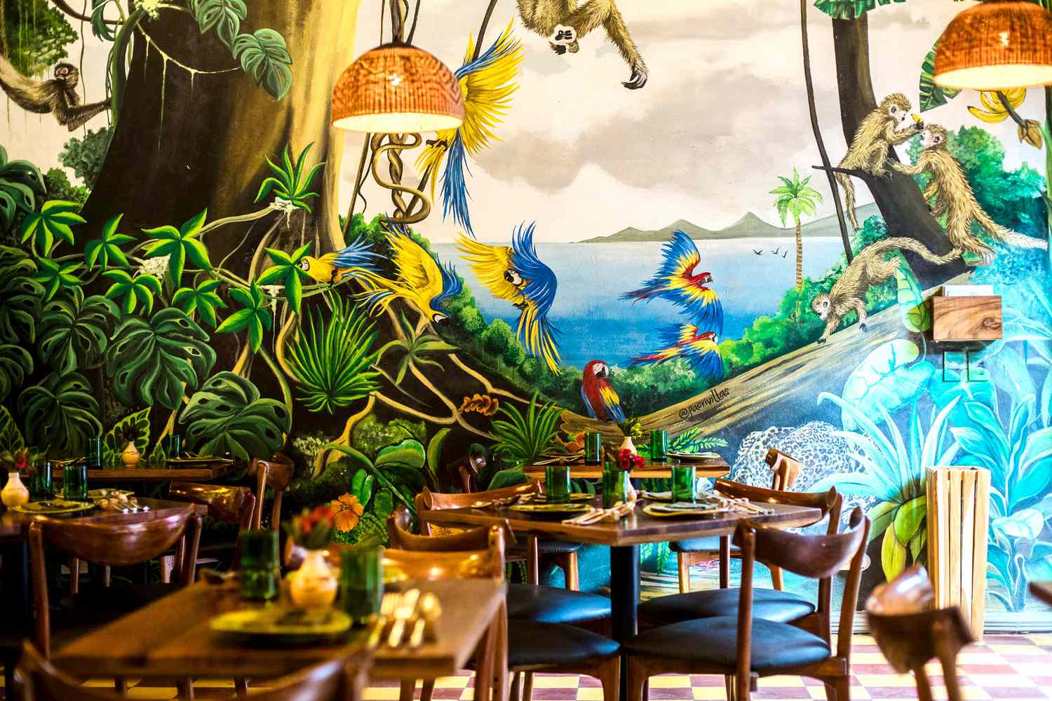 The dining room at Celele in Cartagena, with a painted mural ceiling and plants above the tables
