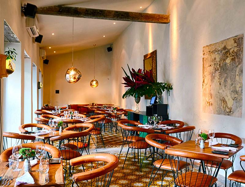 The dining room at Carmen in Cartagena, white walls and set tables under hanging plants