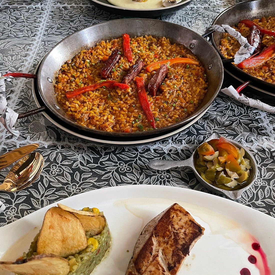 A seafood rice dish served in a pan beside a plated portion