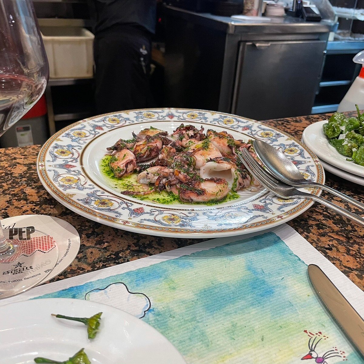 Grilled octopus over green sauce on a patterned plate at Cal Pep, Barcelona