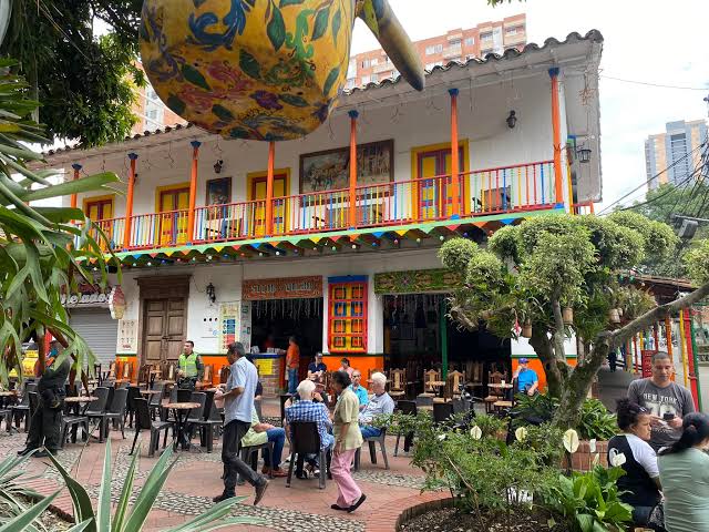 People sitting at outdoor tables outside a colorful café in Medellín