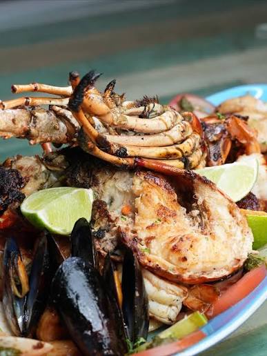 A plate of grilled seafood with mussels, prawns and lime