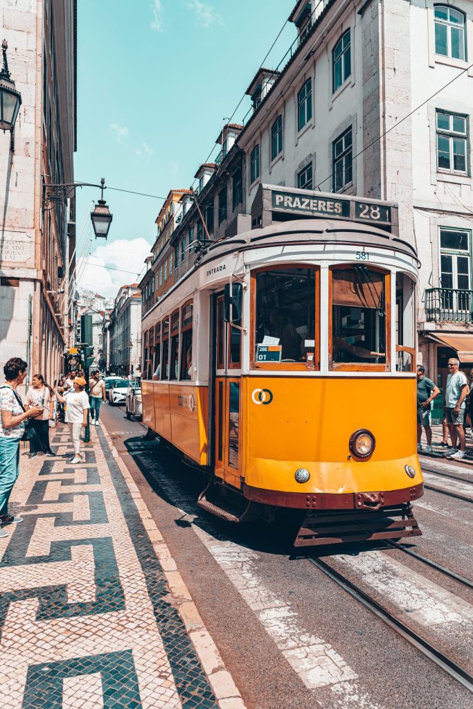 Yellow tram passing over patterned calçada paving in central Lisbon