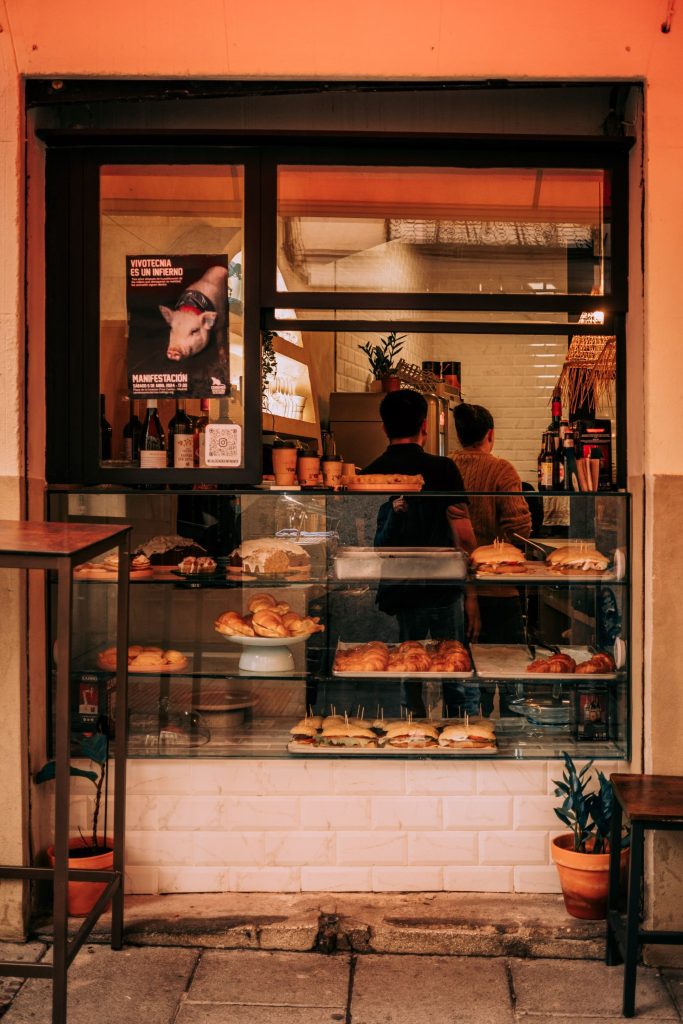 A bakery counter seen from the pavement, staff working behind the glass