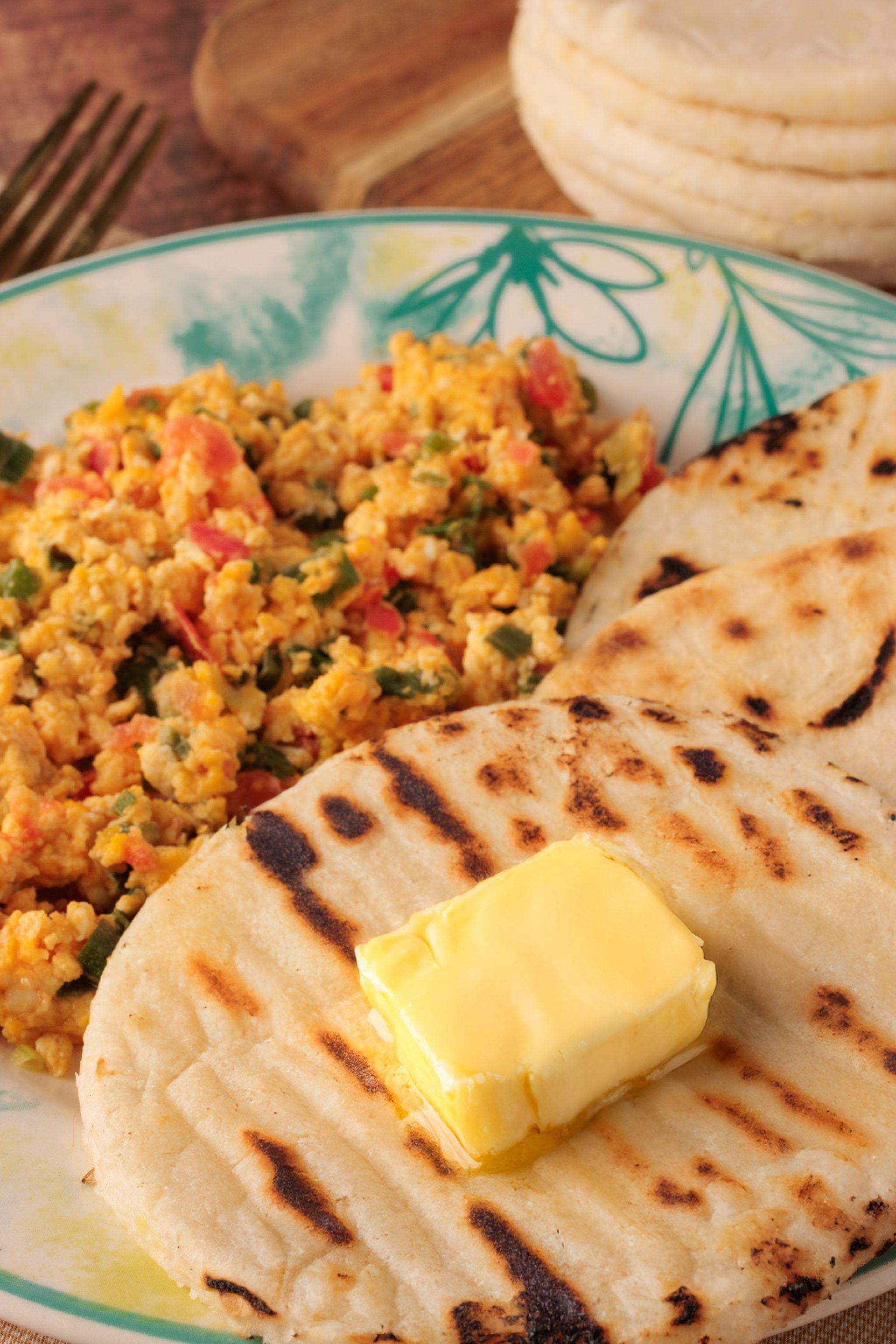 A plate of rice and seafood served with a grilled arepa and butter