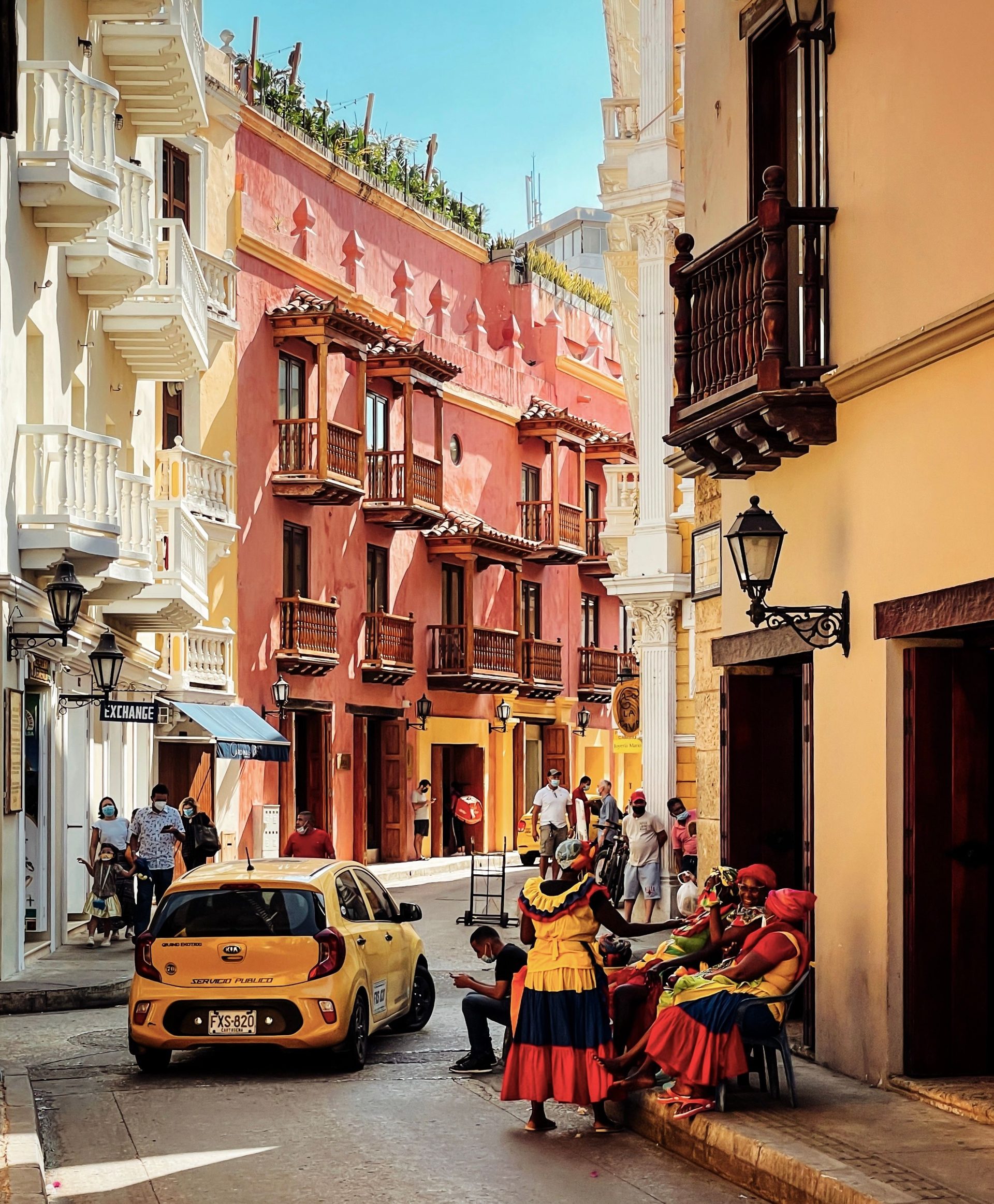 A yellow taxi on a Cartagena street lined with balconied colonial houses