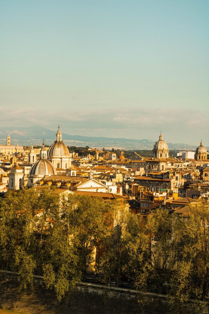 Rome at dusk with domes and rooftops against a deep blue sky