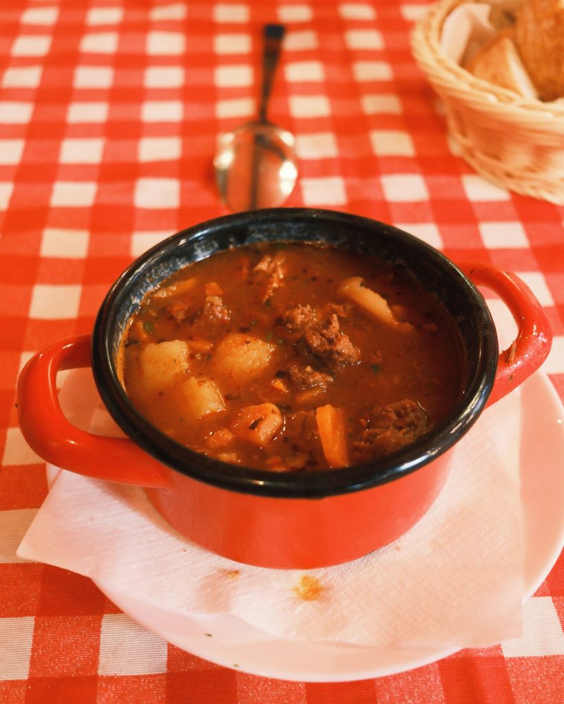 A pot of goulash on a red checked tablecloth