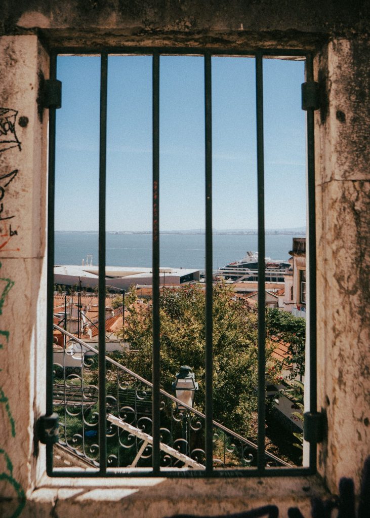 Barred window framing Lisbon rooftops and the river