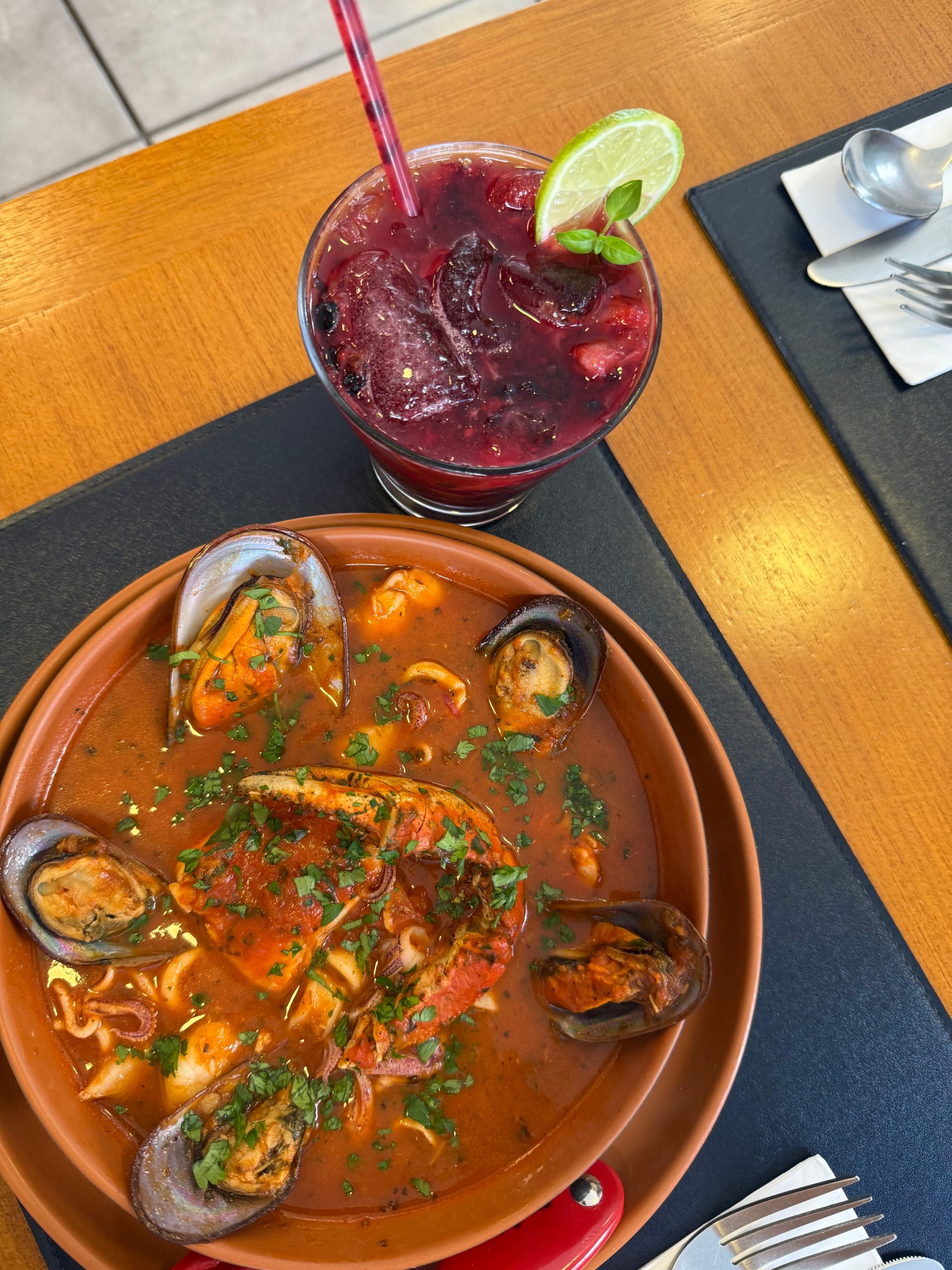 A seafood cazuela beside a red corozo cocktail on a Cartagena table
