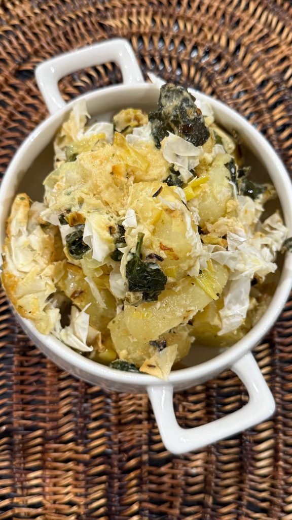 A dish of bacalhau with shredded egg and olives in a white pot