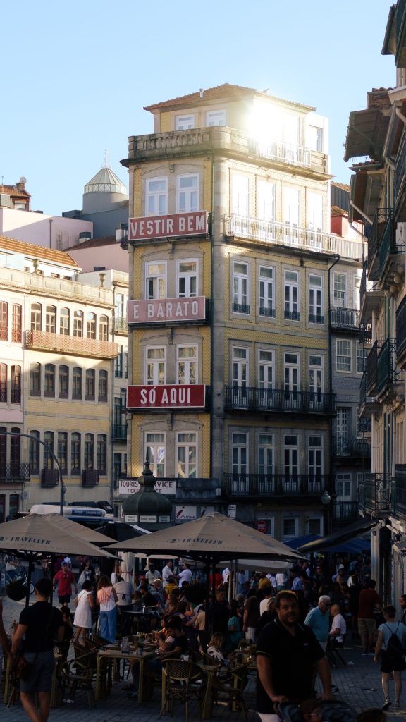 A square of tall tiled buildings with people at outdoor tables