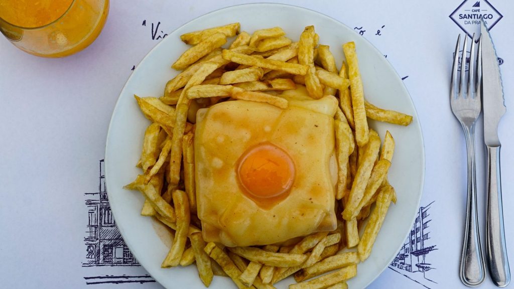 A francesinha with chips and a fried egg on a plate