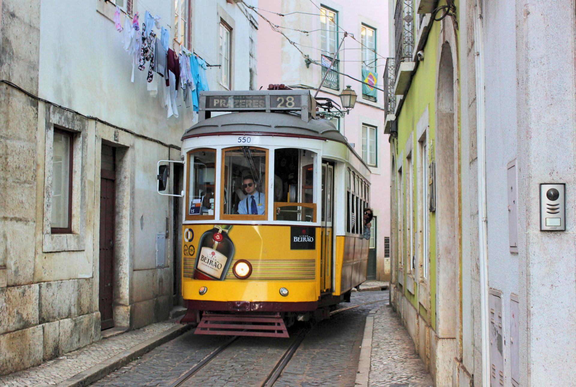 A yellow Tram 28 on a narrow Lisbon street
