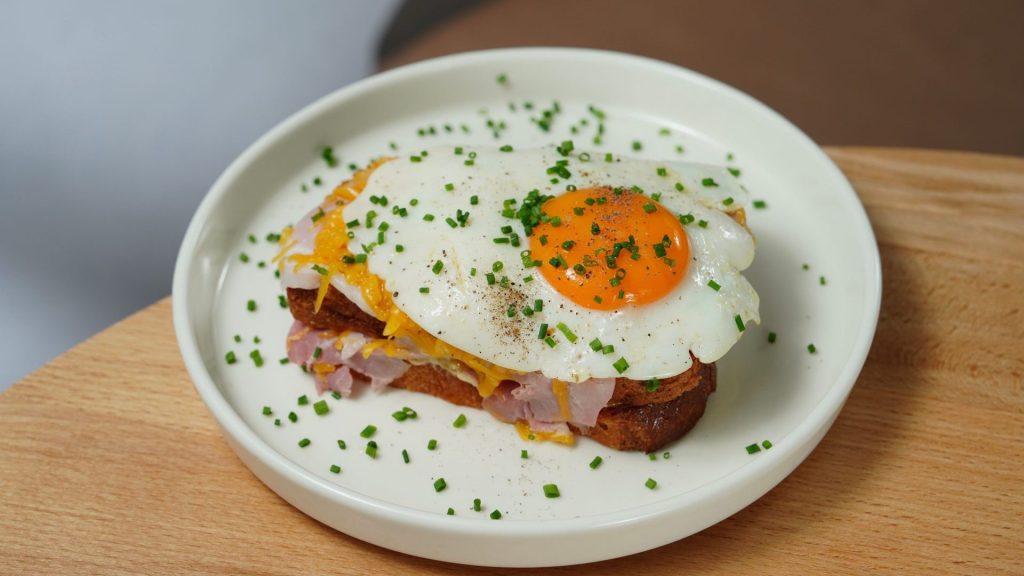 A francesinha topped with a fried egg on a white plate