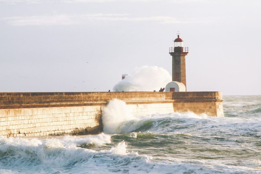 Waves breaking against the lighthouse on the breakwater at Foz