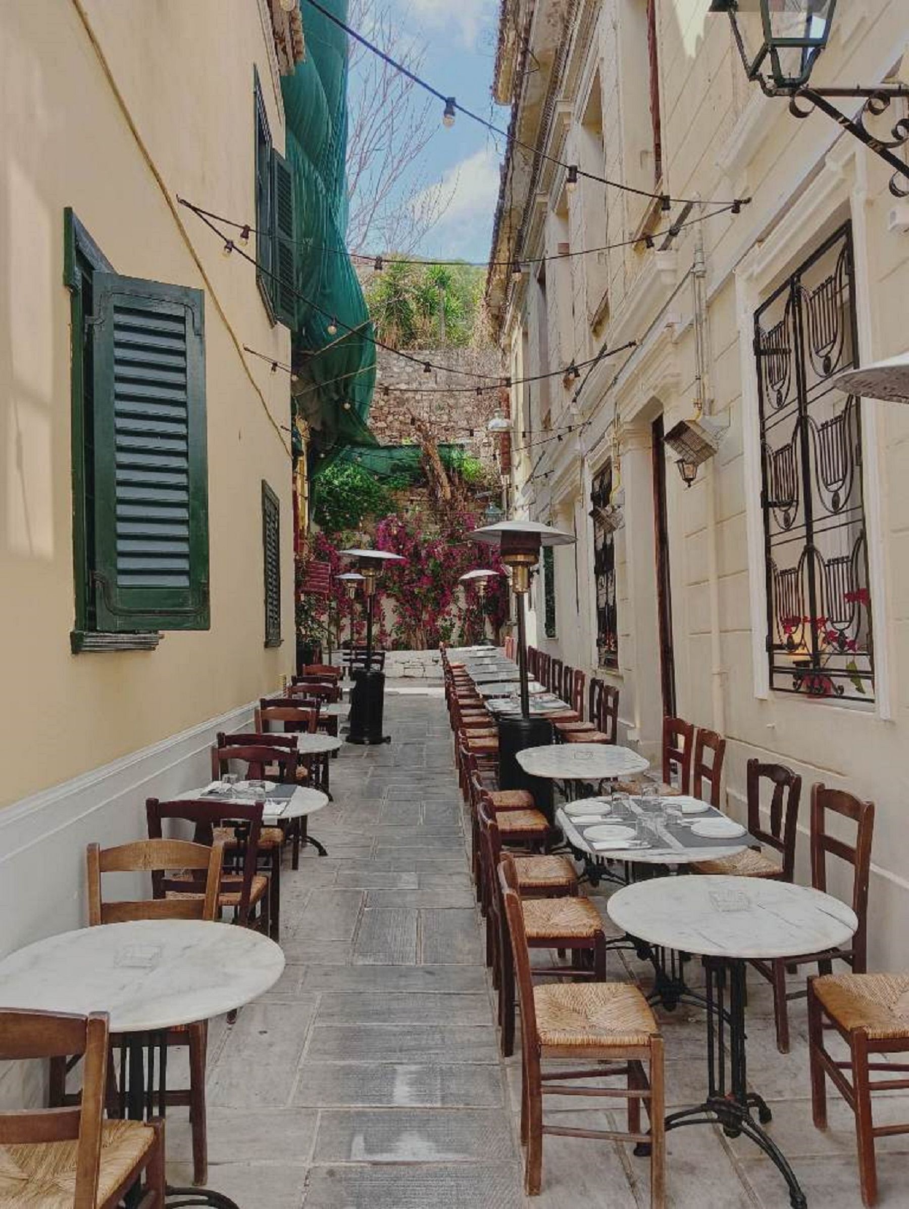 A narrow Athens alley lined with cafe tables