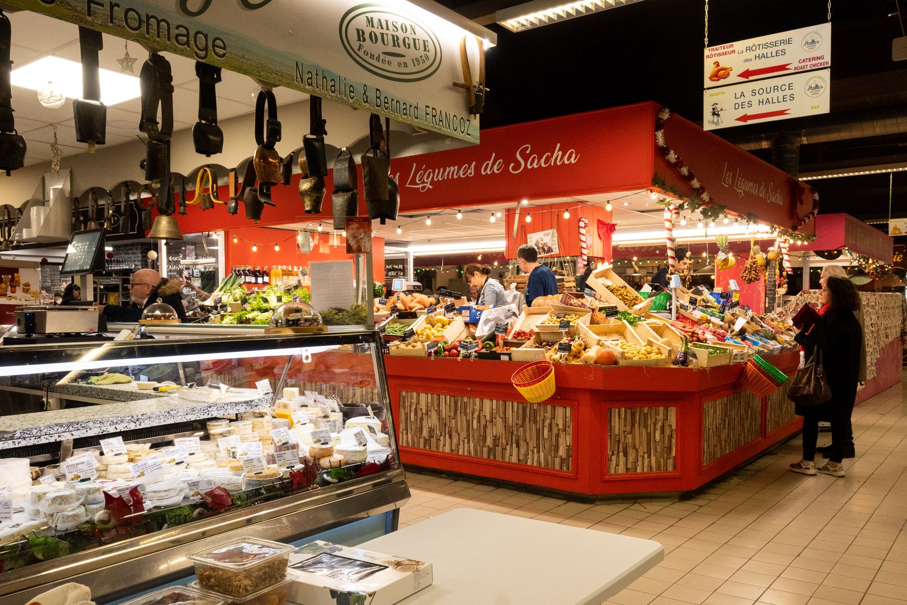 A deli counter stacked with cured meats and cheese inside a covered market hall