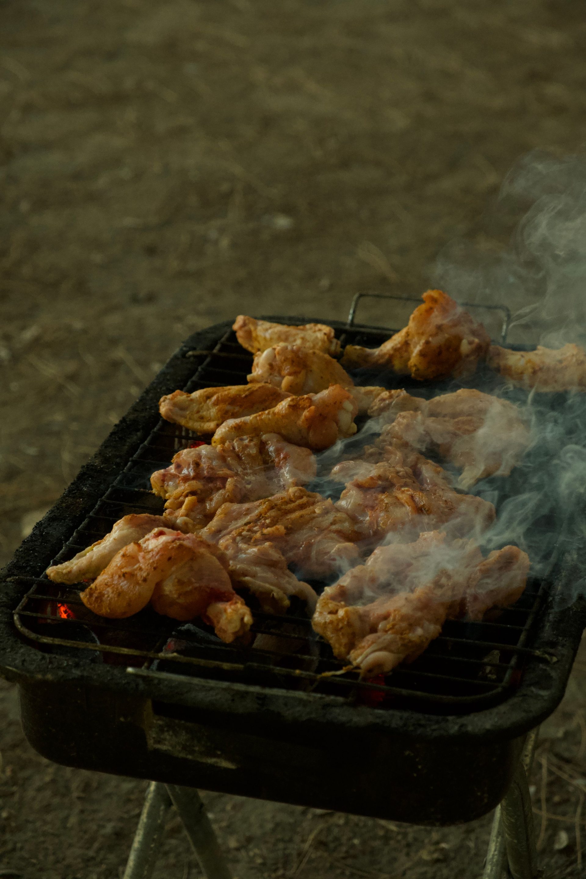 Chicken grilling over a smoky charcoal barbecue