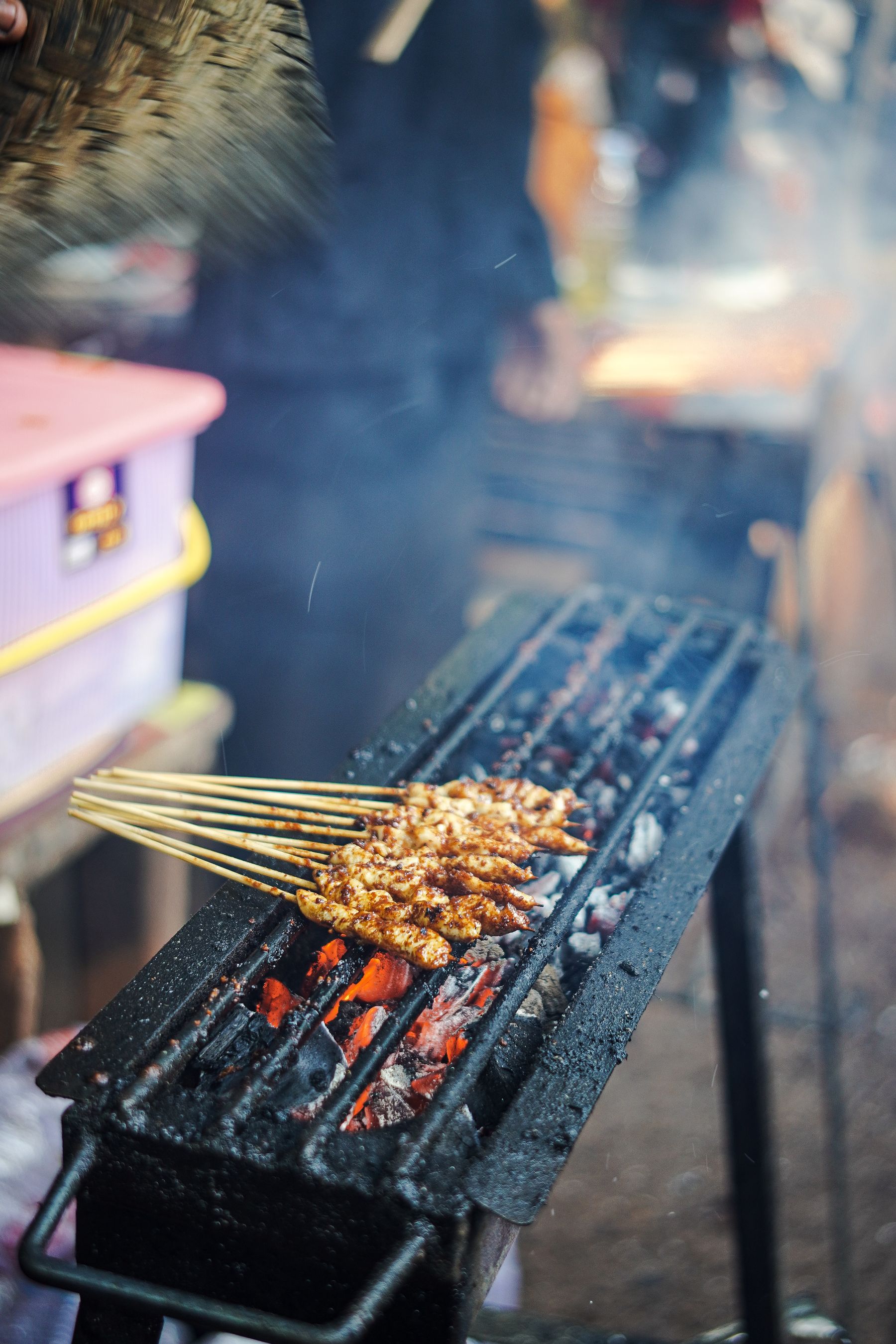 Skewers of marinated pork grilling over charcoal at a street stall