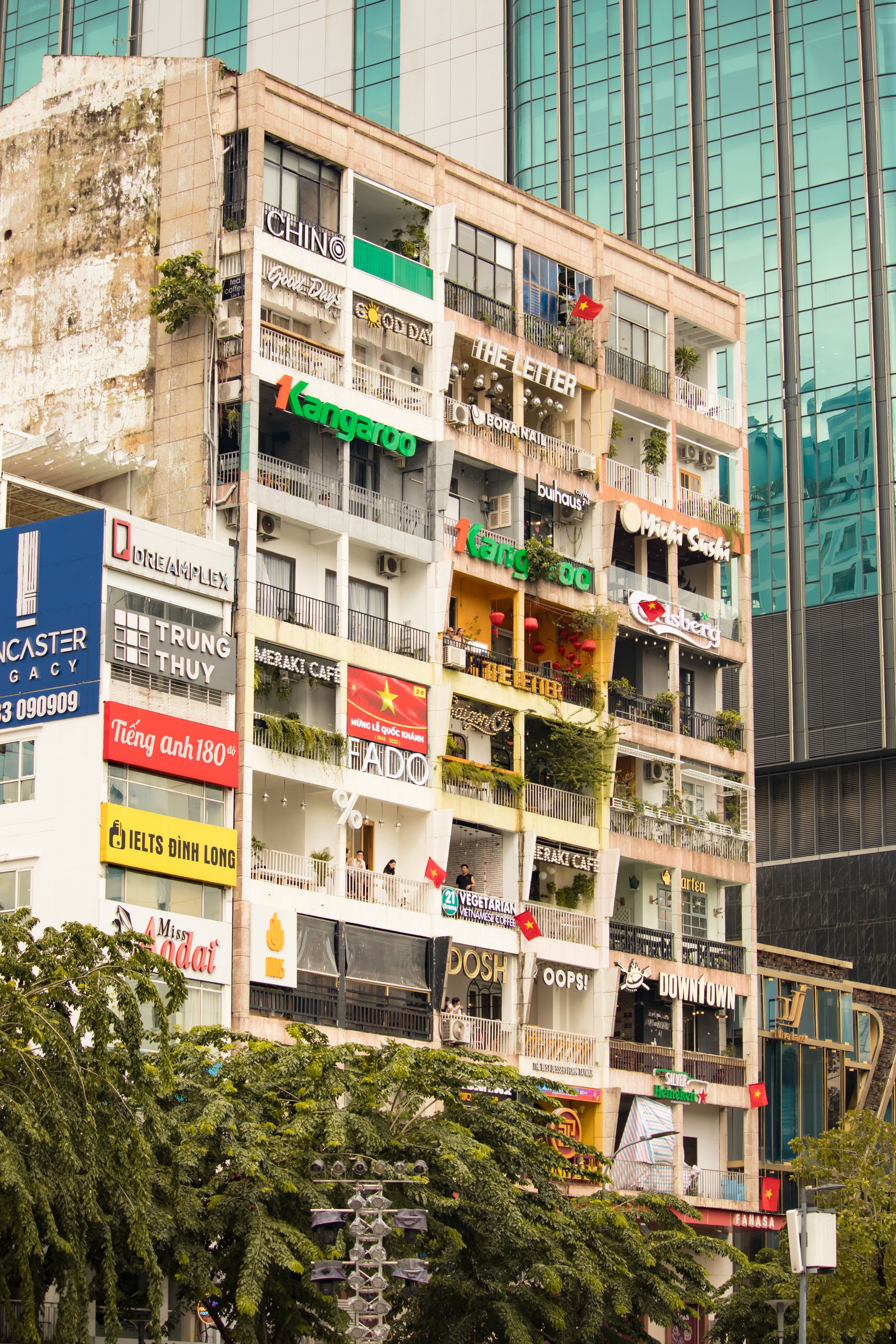 A row of narrow shophouses with signage on a Ho Chi Minh City street