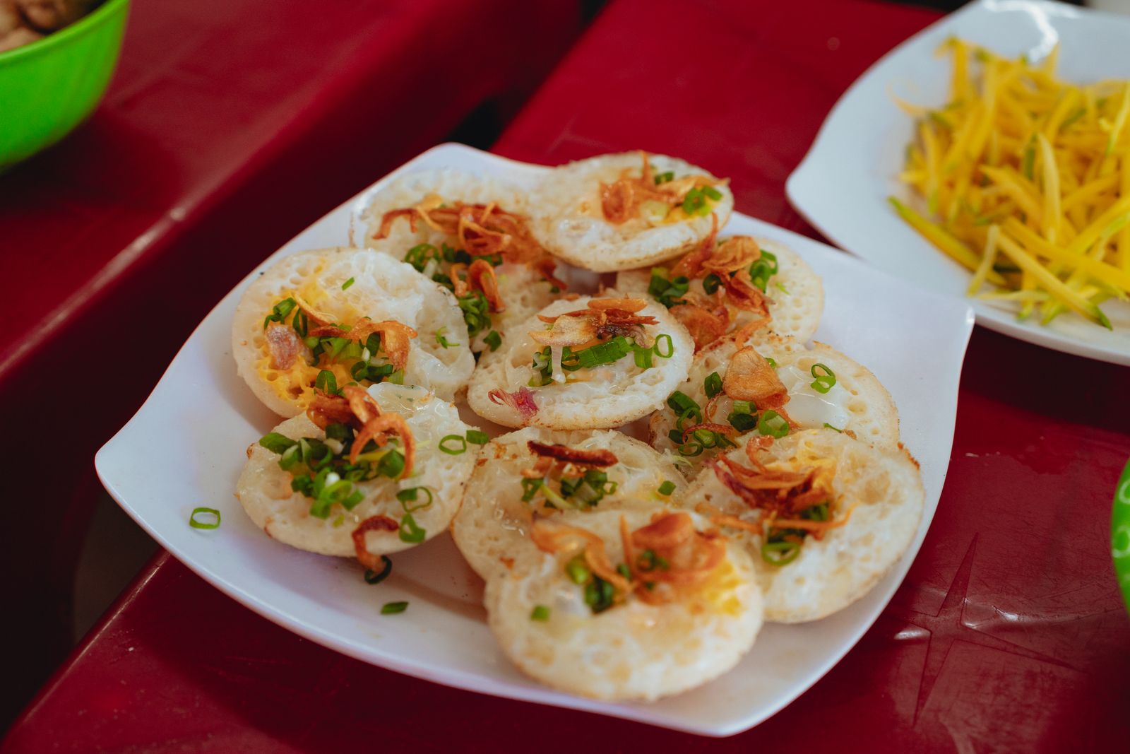 Banh can Vietnamese rice pancakes garnished with scallions and crispy shallots