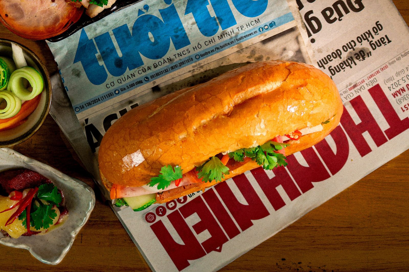 A Vietnamese banh mi on local newspaper, surrounded by fresh ingredients