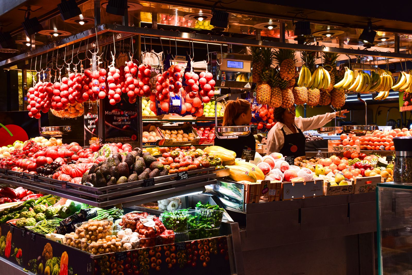 A fruit stand in La Boqueria market, Barcelona, under warm lights