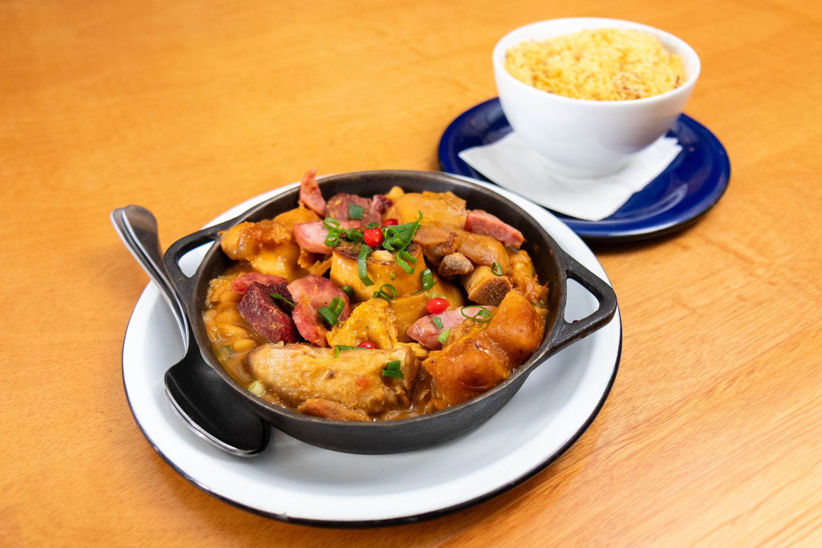 Brazilian feijoada served in a black pot with a side of rice
